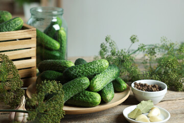 Fresh cucumbers, dill and spices on wooden table, closeup. Preparation for pickling