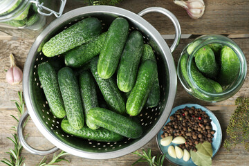 Fresh cucumbers, herbs and spices on wooden table, flat lay. Preparation for pickling