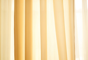 Fototapeta premium Close-up of a yellow curtain with soft folds and light streaming through it