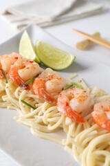 Delicious pasta with shrimps, green onions and lime on table, closeup