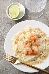 Delicious risotto with shrimps and cheese on grey table, top view