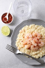 Delicious risotto with shrimps and cheese served on light grey table, top view