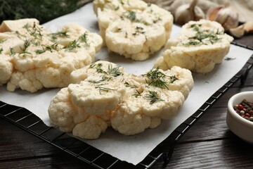 Uncooked cauliflower steaks with spices on wooden table, closeup