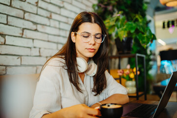 Young caucasian woman working or studying on laptop from cafe	