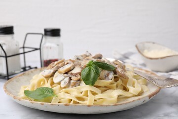 Delicious pasta with mushrooms and basil on white marble table, closeup