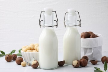 Bottles of macadamia milk and nuts on white tiled table