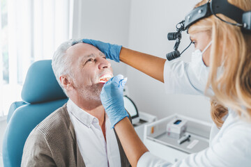 Doctor checking man throat with medical stick