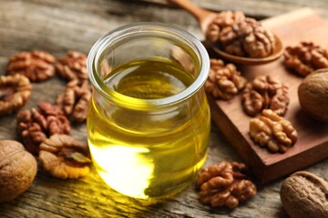 Walnut oil in jar and ingredients on wooden table, closeup