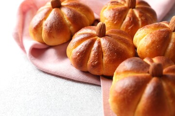 Tasty pumpkin shaped buns on light textured table, closeup