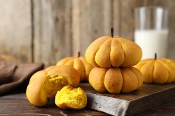 Tasty pumpkin shaped buns on wooden table, closeup