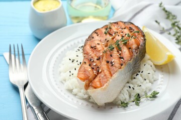Tasty grilled salmon steak with rice, thyme, lemon and sesame seeds on light blue wooden table, closeup