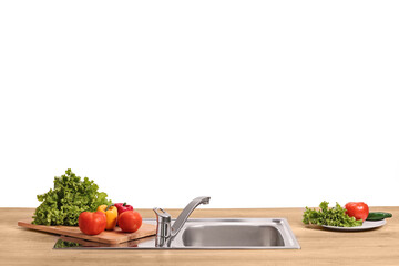 Vegetables on a wooden counter and a stainless steel kitchen sink
