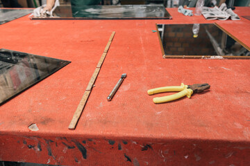Artisan workplace featuring a red table, measuring tools, and remnants of crafting materials