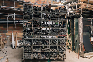 A shelf with metal materials of different sizes in a glass workshop