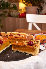 pumpkin pie on a wooden tray stands white on a table on the background of a white chair side view 