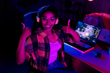 Photo of young woman demonstrate thumb up play gaming laptop esport neon light night apartment...