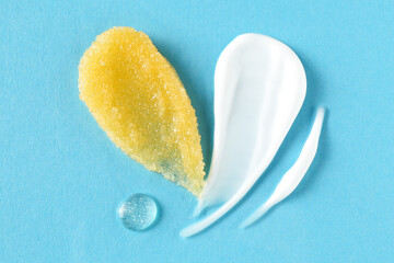 Smears of cosmetic products on light blue background, top view