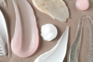 Smears of different cosmetic products on grey background, flat lay