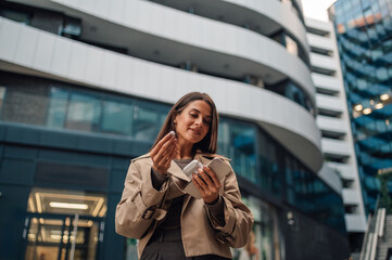 Businesswoman putting earbuds on in front of office building