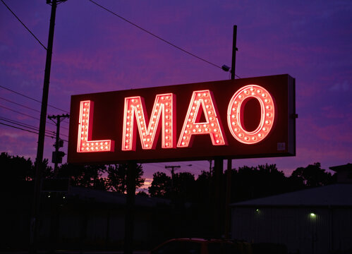 LMAO laughing light sign text for reaction, funny concept art, glowing letters in the purple night in a small America town