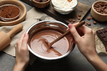 Woman making chocolate dough at grey table, closeup