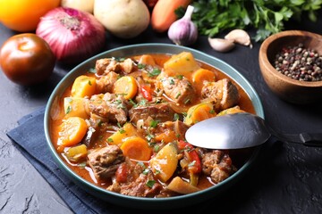 Delicious stew and different ingredients on black table, closeup