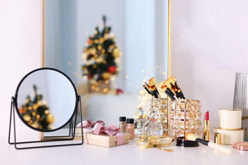 Makeup brushes, cosmetics, mirror and perfume on white table indoors