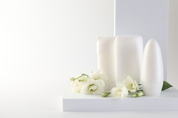 Different deodorants and beautiful eustoma flowers on white background, space for text