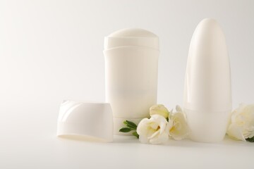 Different deodorants and beautiful eustoma flowers on white background