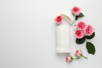 Solid deodorant and beautiful rose flowers on white background, flat lay. Space for text