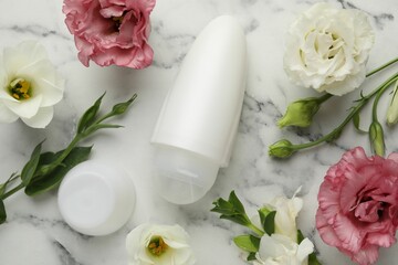 Roll-on deodorant and beautiful eustoma flowers on white marble table, flat lay
