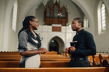 Priest listening to woman talking in church
