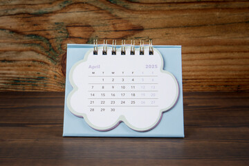 April 2025. Cardboard desk calendar on a wooden texture background