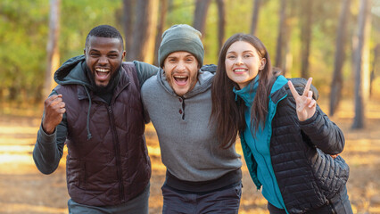 Emotional international group of tourists posing over autumn forest background