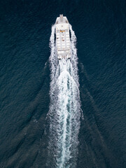Vue aerienne d'un bateau blaanc avec sillage sur une eau bleue