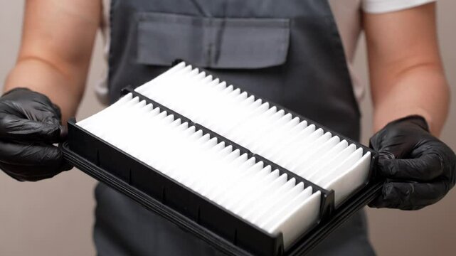 Man holding and rotating new car air filter in hands, close-up. Concept of auto parts replacement, air filter, car maintenance. 