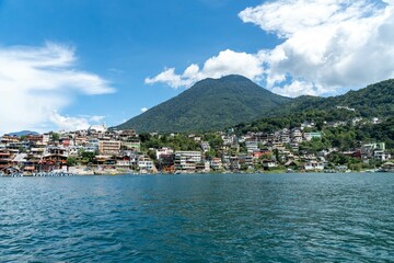 nature landscape during cloudy and sunny day at a lake with buildings and mountains in foreground with a lagoon