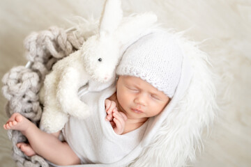 A cute newborn baby in a bunny hat with ears is sleeping sweetly in a basket