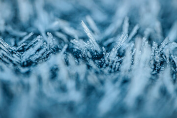A stunning macro shot showcasing intricate ice crystals forming in a cold environment. The delicate structures of the crystals rise in various shapes, creating a mesmerizing natural pattern of frost