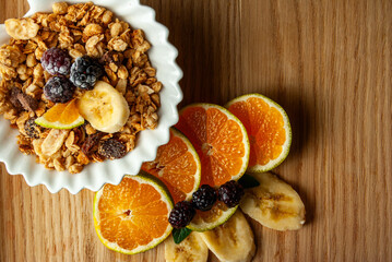 A breakfast bowl filled with nutritious oat flakes, fresh blackberries, juicy tangerine slices, and sweet banana pieces.