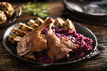 Portion of roast duck leg red cabbage homemade dumplings on plate and red wine on the background