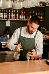 Skilled bartender artfully pouring colorful cocktails in a lively bar setting during the evening rush