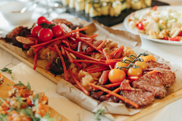 Grilled sausages and chicken on wooden board on buffet table