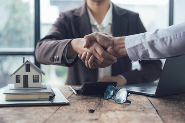 Real Estate Deal Closed: A handshake seals the deal between a real estate agent and a client,...