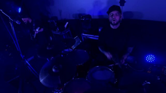 The drummer cool plays the rock concert. View from the action camera, go pro. A man energetically drumming on stage with vibrant lights illuminating behind him. A drummer performing live, surrounded 