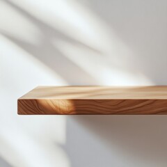 A smooth, polished wooden shelf mounted against a white background, casting soft shadows and illuminated by natural light