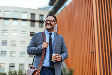 Smiling Businessman Outdoors with Coffee and Bag in Urban Setting