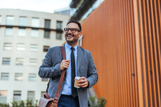Smiling Businessman Outdoors with Coffee and Bag in Urban Setting