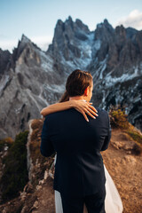 The bride and groom are hugging on top of the rock