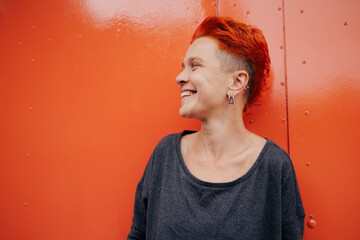 Smiling woman with vivid hair standing near garage door
